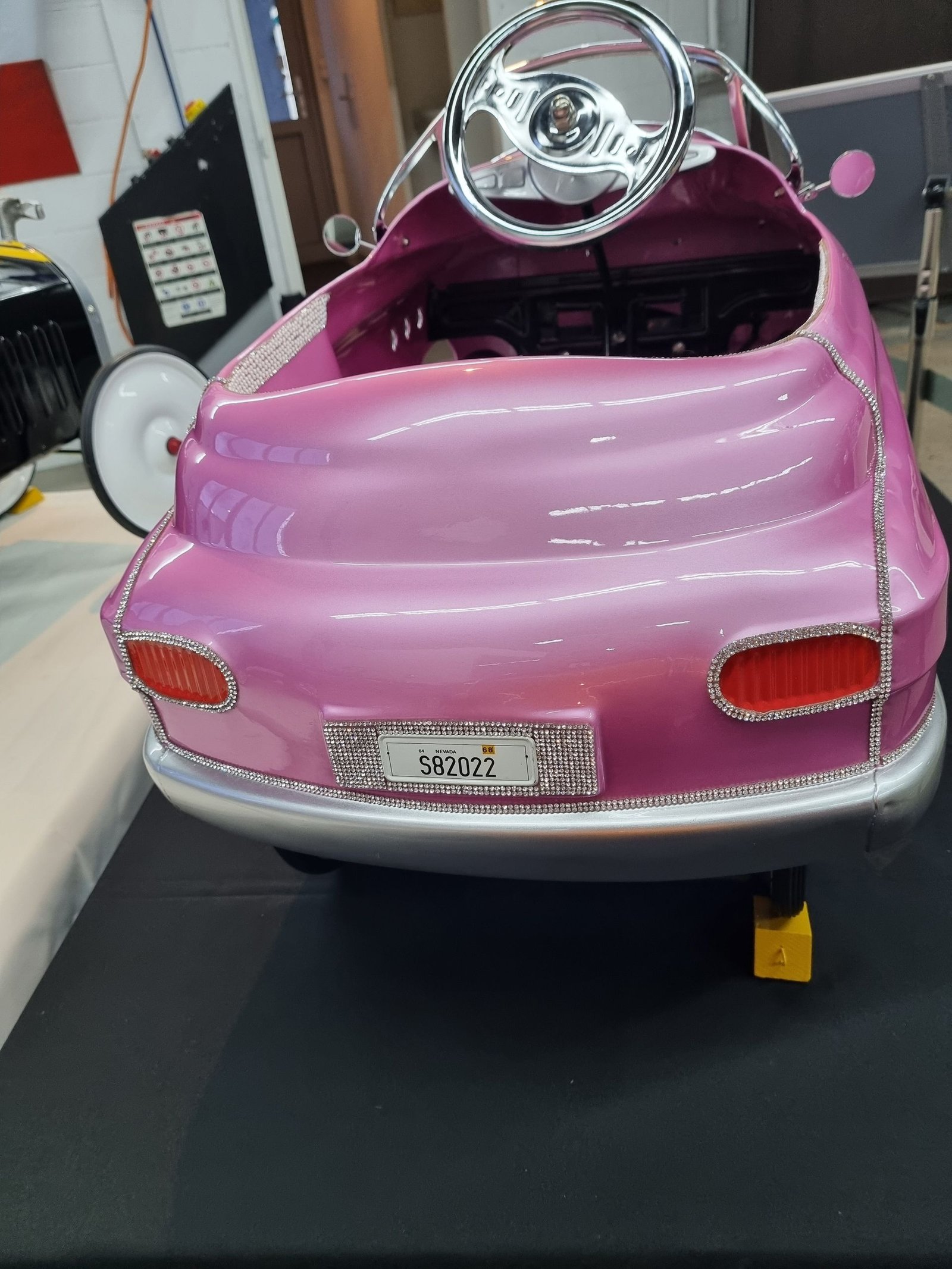 Ein rosa Tretauto steht auf einem Tisch